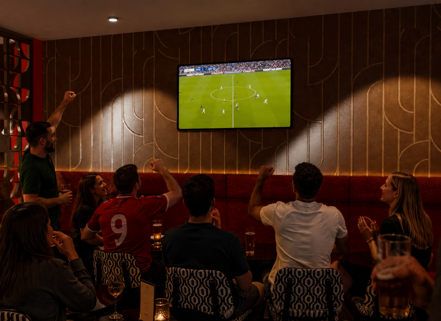 Guests watching live football on the big screen, drinks in hand